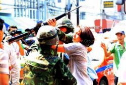 Una mujer intenta arrebatarle el fusil a un soldado