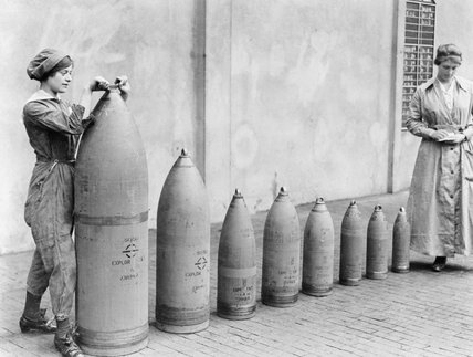 Two women munitions workers stand beside examples of the shells produced at National Shell Filling Factory No.6, Chillwell, Nottinghamshire during the First World War. Nicholls Horace © IWM (Q 30017)